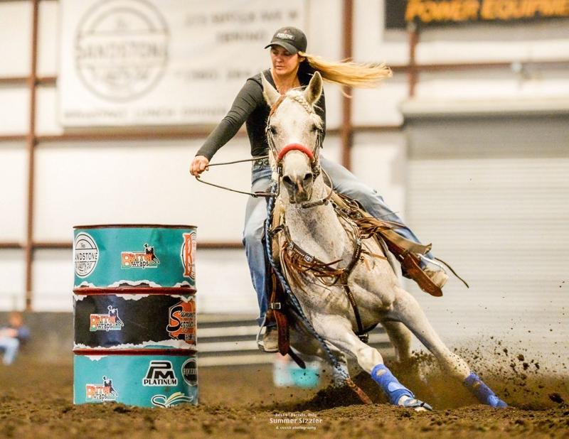 April Sansevere riding a gray horse around a barrel